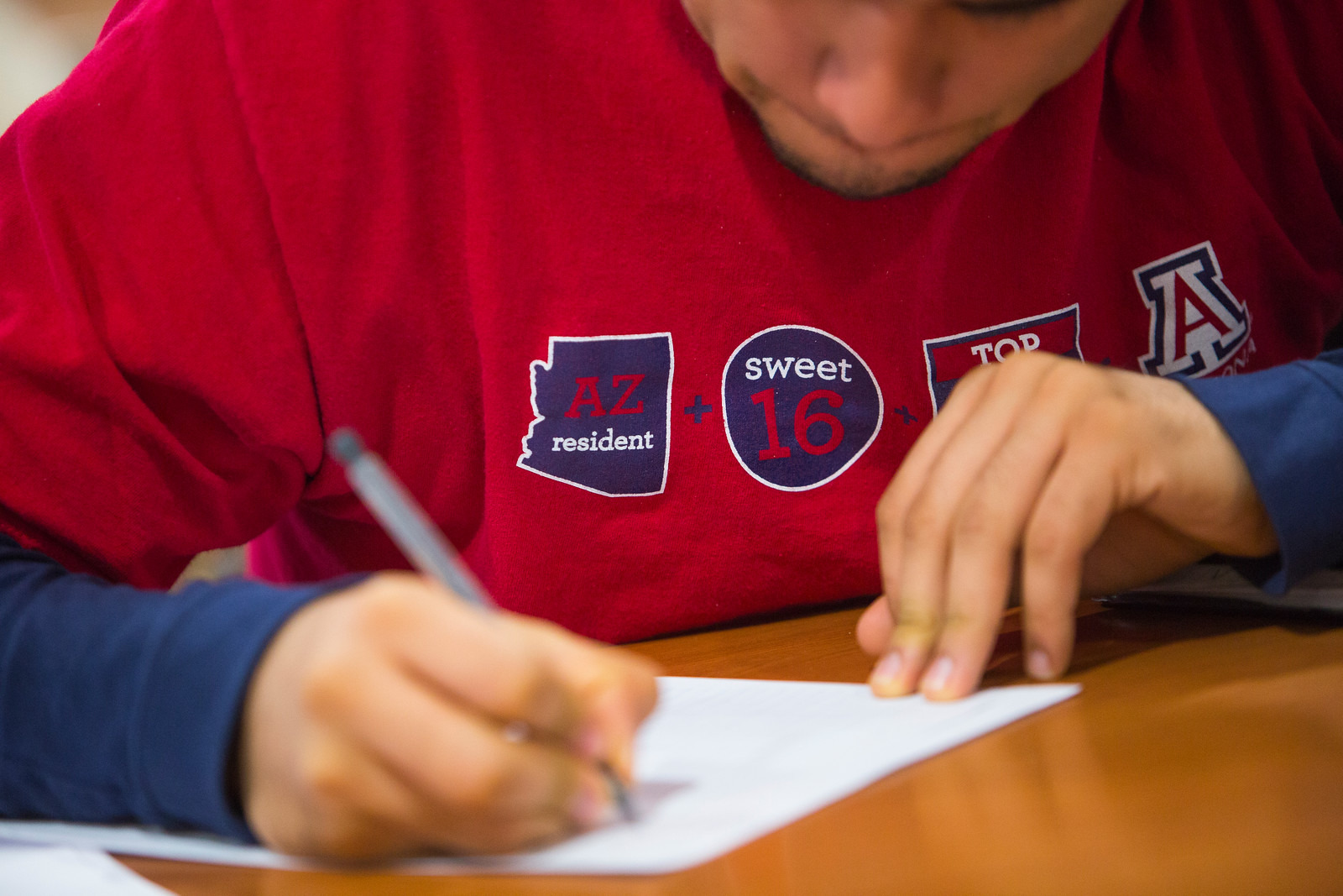 Student in red Arizona shirt writing